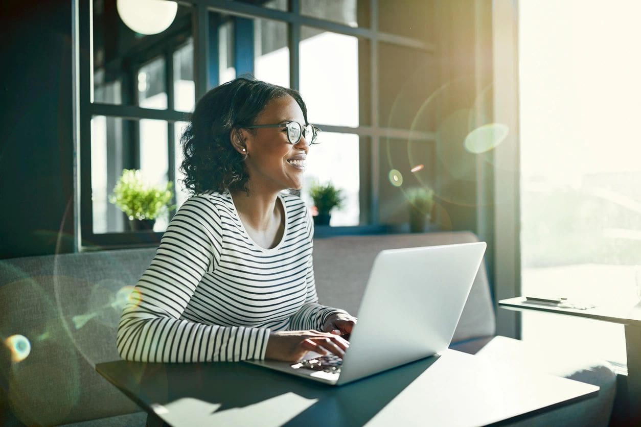 A woman sitting at a table with her laptop.